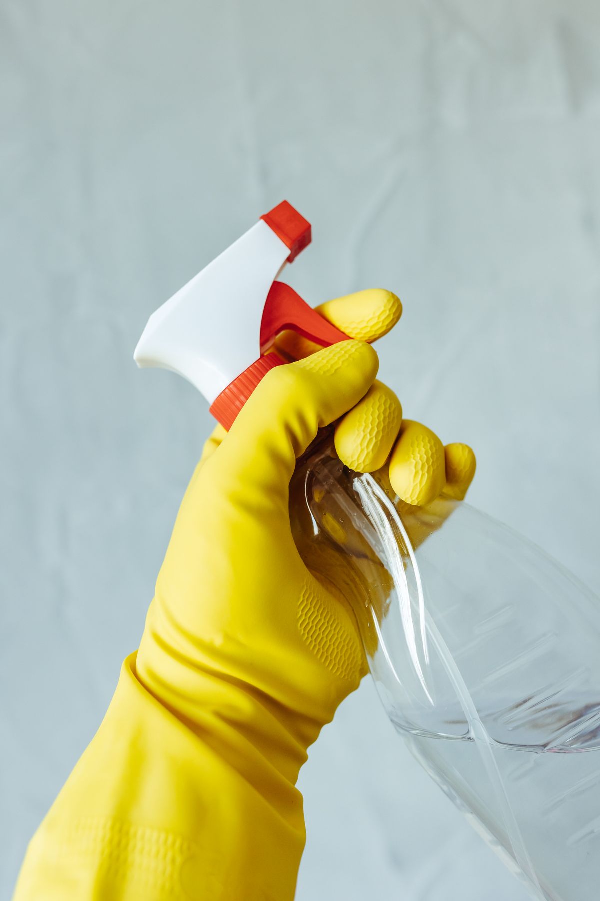 Close-up of a gloved hand holding a spray bottle for deep cleaning