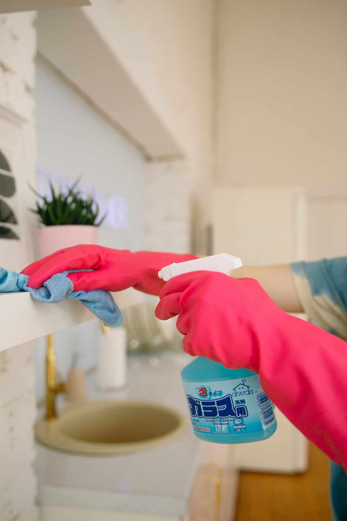 Person using a spray bottle and cloth to clean a shelf area